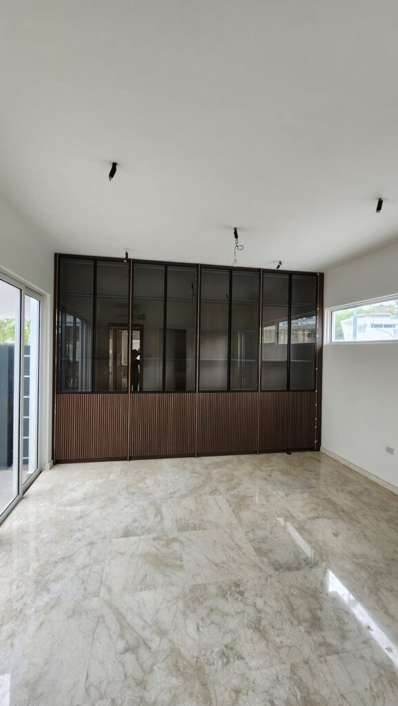 Room with marble tiled floor and a floor-to-ceiling fluted-wood and black-framed glass partition wall. Jade Hills, Kajang, Selangor.