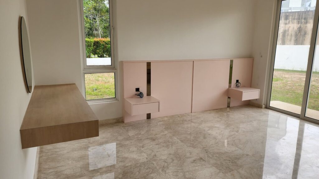 Bedroom with marble floor, a pink built-in headboard with side tables and reading lamps, a floating wooden bench. Jade Hills, Kajang, Selangor.