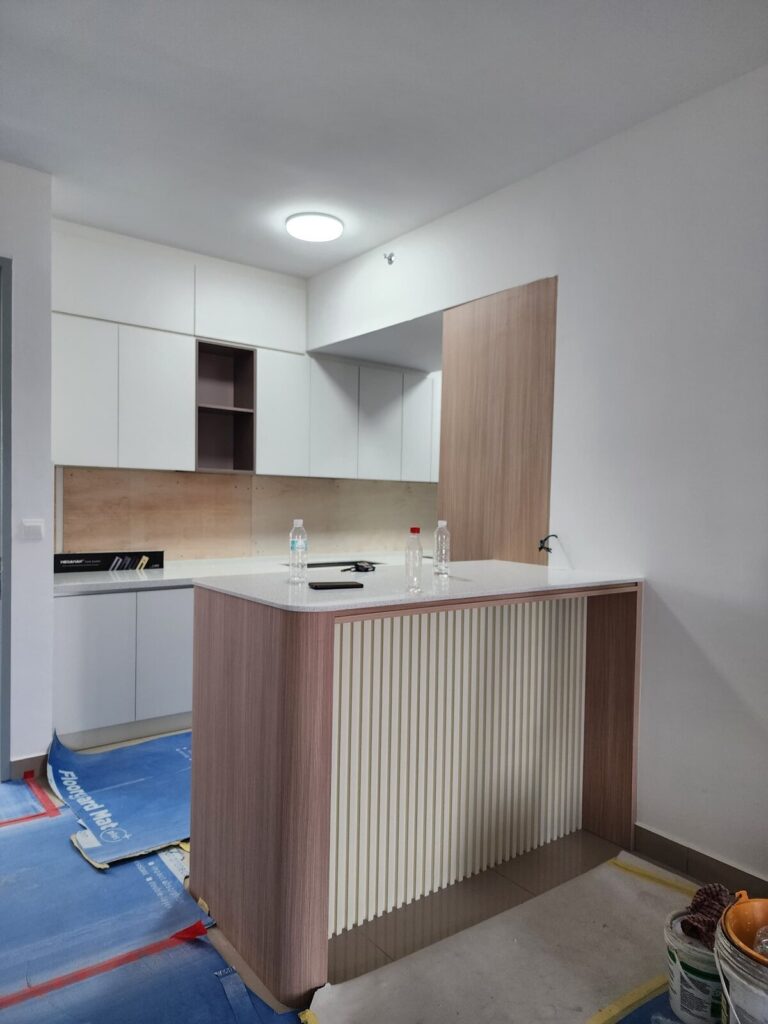 The same white kitchen with overhead cabinets, open shelves and a wood-veneer breakfast bar with vertical fluted detail. M Zenya, Kuala Lumpur.