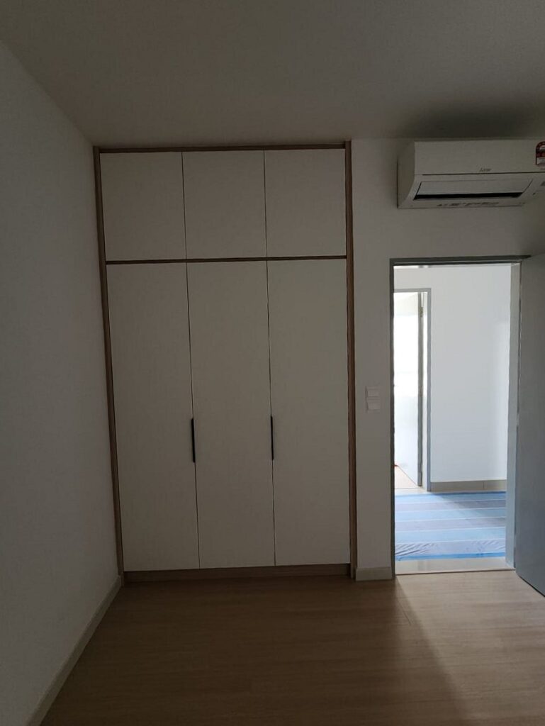 Bedroom with a built-in white wardrobe with overhead cabinets and light wood trim, a wall-mounted Mitsubishi air conditioner. M Zenya, Kuala Lumpur.