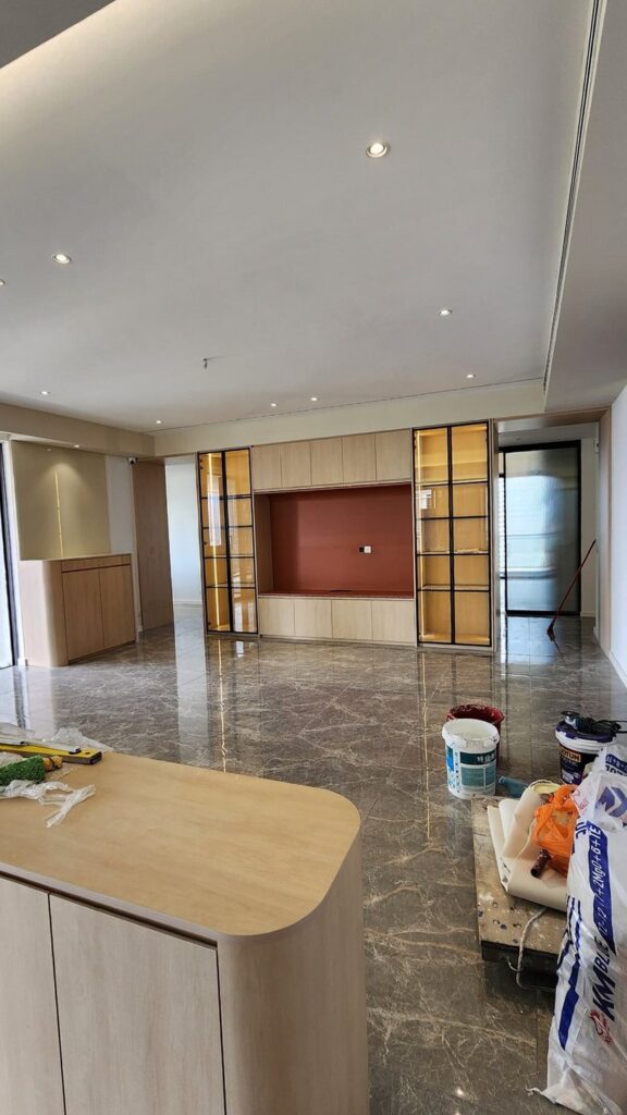 Spacious finished interior with marble floor, recessed lighting, wood-veneer cabinetry with glass display cases and a red-orange TV niche. Park Regent, Desa ParkCity, Kuala Lumpur.