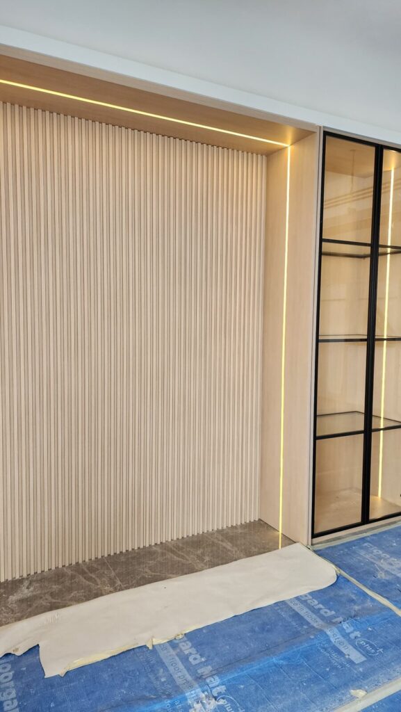 Finished wood-slat feature wall with LED lighting next to a black-framed glass display cabinet. Park Regent, Desa ParkCity, Kuala Lumpur.