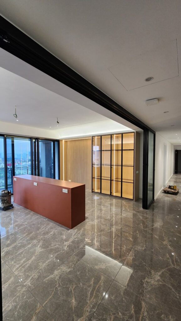 Finished interior with polished marble floor, a red/orange low counter and a black-framed gridded glass partition. Park Regent, Desa ParkCity, Kuala Lumpur.