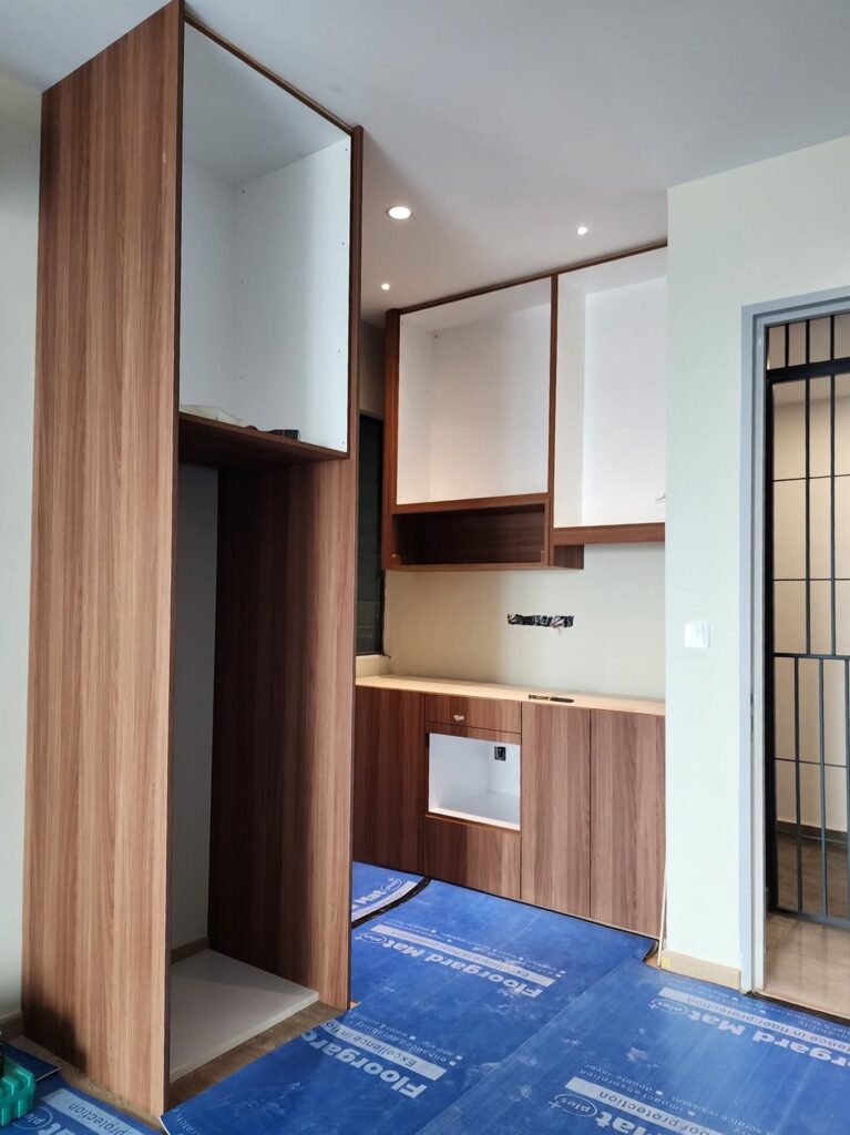 Wood-veneer kitchen cabinetry with white upper units and lower counter installed in a renovated room. Resident Ruby, Sea Park, Petaling Jaya, Selangor.