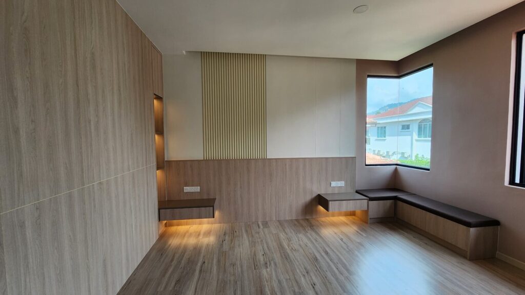 Unfurnished room with wood-grain walls, fluted accent panel, floating shelves with under-lighting and an L-shaped corner bench beneath a bay window with a hill and houses outside. Saujana Akasia, Shah Alam, Selangor.